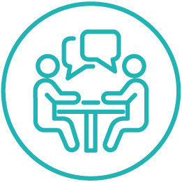 Icon of two peoplw talking at a table with speech bubbles.